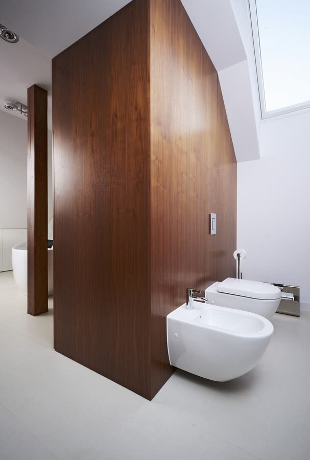 Wannę od toalety oddziela drewniana zabudowa w...