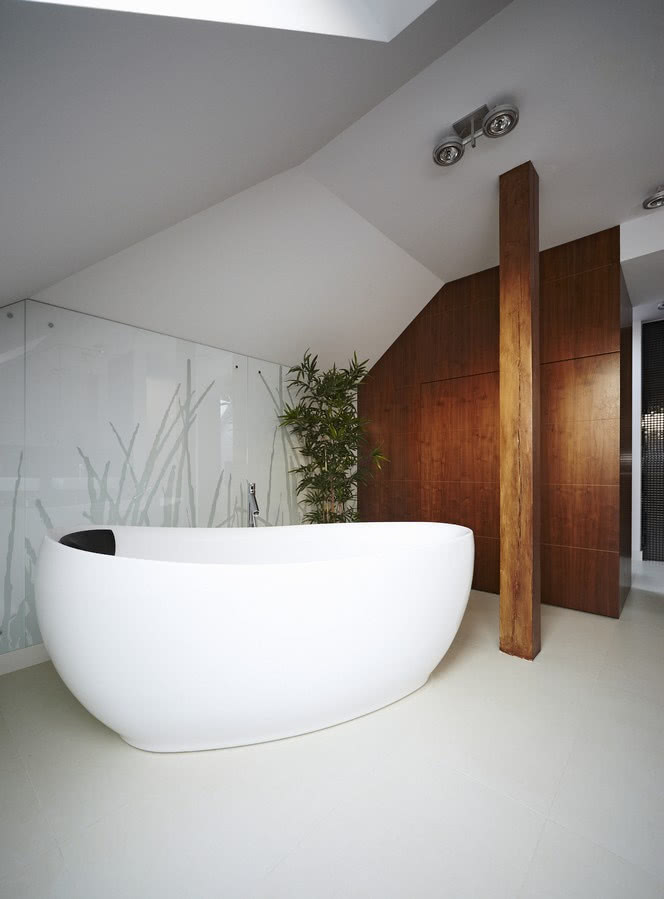 Ściana nad wanną została wykończona szkłem z...