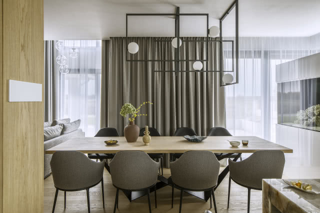 Stół jadalniany z szarymi krzesłami, nad nim oświetlenie