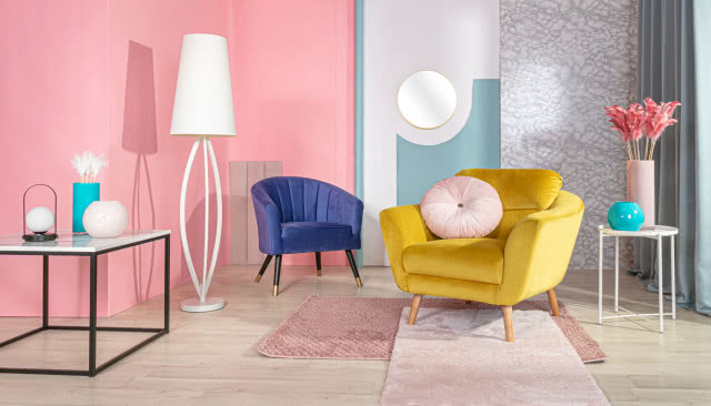 niebieski fotel, żółty fotel, lampa podłogowa biała, stoliki kawowe, wazony, lustro, różowa ściana, drewniana podłoga