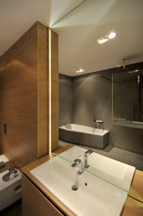 Duże lustro umieszczone nad umywalką w łazience optycznie powiększa wnętrze.