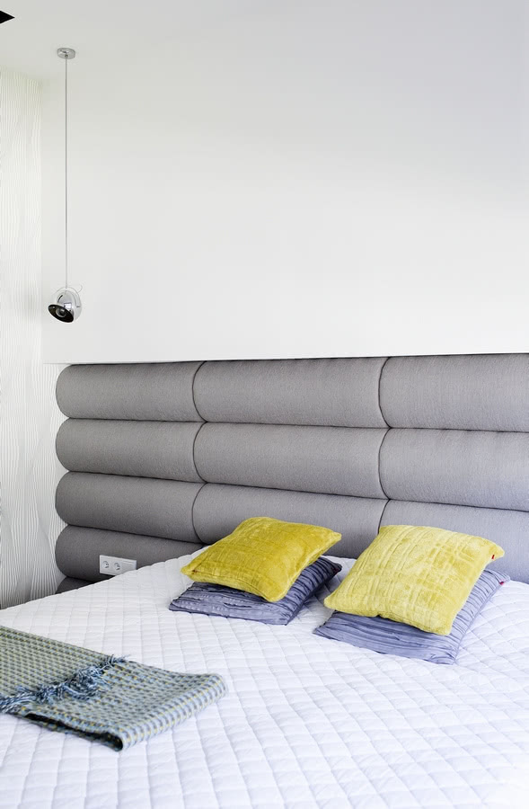 Zagłówek łóżka z obitych szarą tkaniną rolek to...