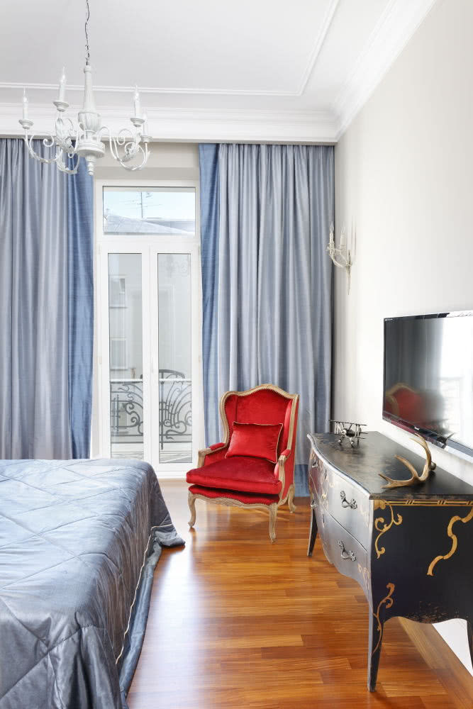 Czerwony fotel uszak ożywia stylowa sypialnię