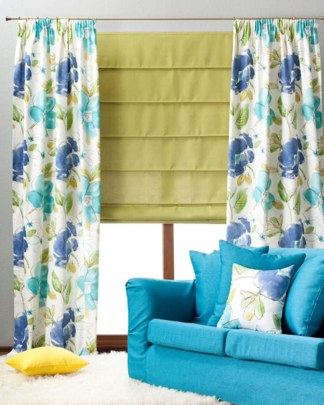 Roleta w kolorze zielonym, zasłony w duże niebieskie kwiaty, niebieska kanapa