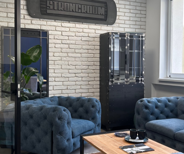 biała cegła na ścianie, witryna, niebieska kanapa, drewniany stolik kawowy