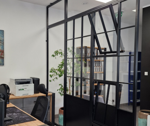 ścianki z przeszkleniami, biurko, drukarka, fotel obrotowy, kwiat w doniczce, regał na książki i segregatory, obraz