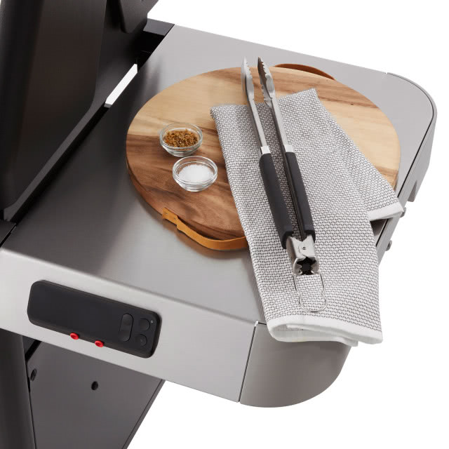 duży blat roboczy, drewnia deska do krojenia, przyprawy, szczypce do przewracania mięsa i warzyw, ściereczka