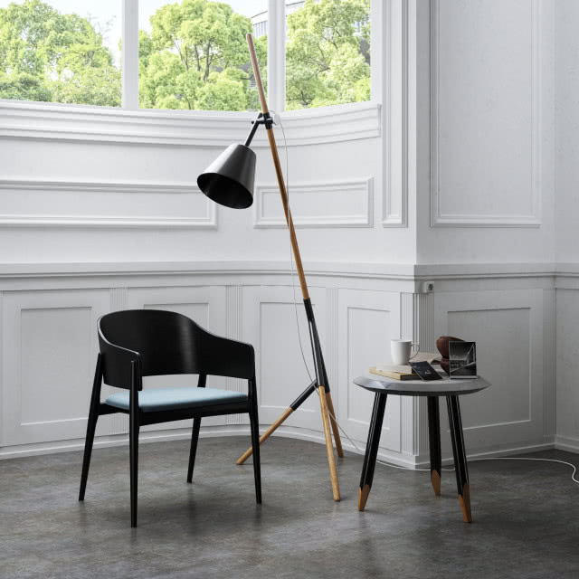 czarne krzesło z siedziskiem, lampa podłogowa, stolik kawowy, kubek, książka, sztukateria na ścianie