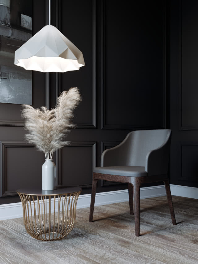 krzesło w skurzanej tapicerce, stolik kawowy, wazon z suchą trawą, obrazy, ciemna sztukateria na ścianie, drewniana podłoga