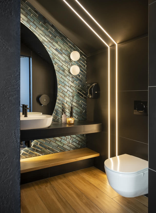 łazienka z zielonymi płytkami i dużym lustrem