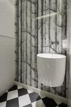 W osobnej toalecie ścianę wykończono tapetą z czarno-białym rysunkiem drzew