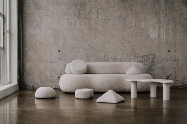 biała sofa na tle szarej ściany