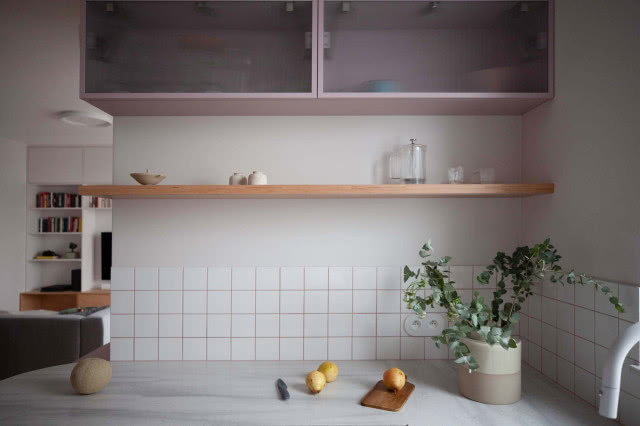 różowe przeszklone szafki kuchenne wiszące, drewniana półka, kwiat w doniczce, biała bateria zlewozmywakowa