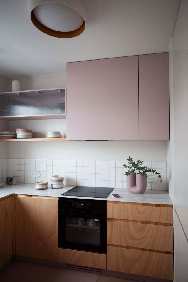 różowe fronty szafek kuchennych wiszących, drewniane fronty szafek dolnych,  półki, piekarnik, miseczki, talerze, okap