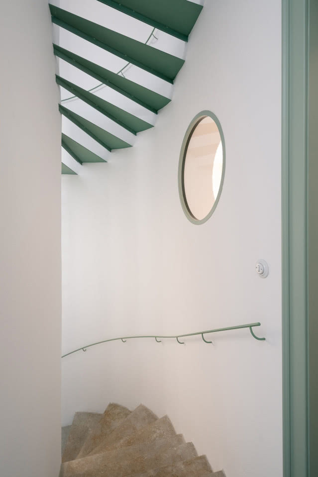 zielone schody z poręczą i okrągłe okno