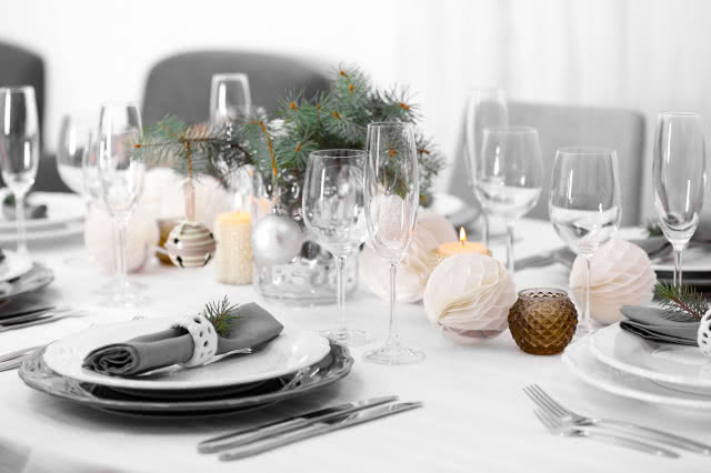 biały obrus, biała zastawa stołowa, białe bombki z papieru, gałązki świerku, sztućce