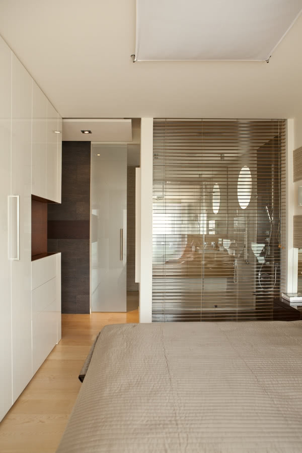 Za szklaną ścianą sypialni jest prysznic.