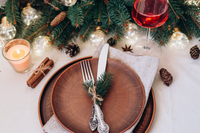 kremowy bieżnik, gałązki świerku, biała zastawa stołowa, świeczki, kieliszki