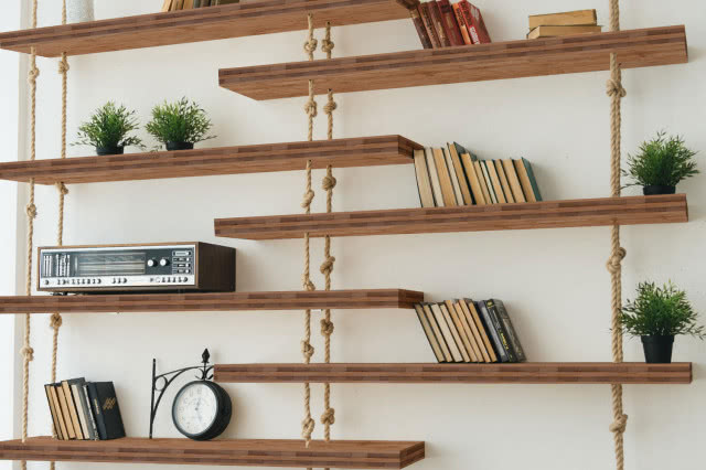 półki zrobione z drewnianych blatów, książki, budzik, radio, kwiaty