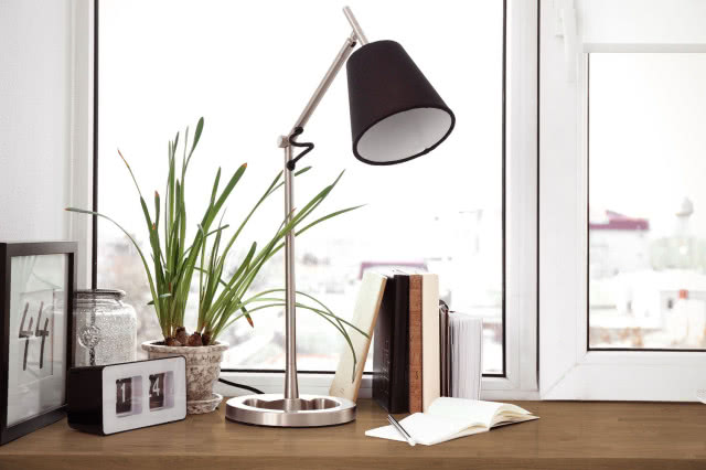 drewniany parapet, lampa biurkowa, zegar, obraz, książki, ramka na zdjęcia, kwiat