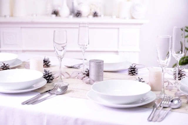 biały obrus, biała zastawa stołowa, białe bombki z papieru, gałązki świerku, sztućce
