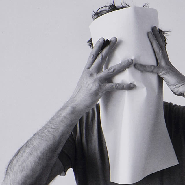 człowiek zakrywający sobie twarz gazetą