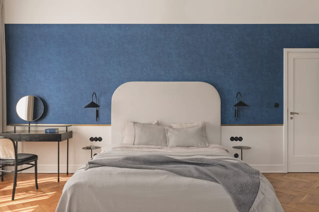 niebieska ściana w sypialni i białe łóżko
