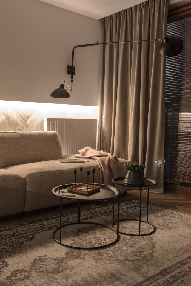 Klimatyczny salon z beżową sofą i industrialnym oświetleniem