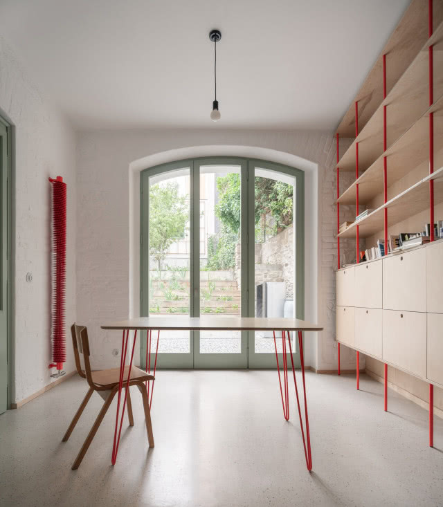 pokój z czerwonymi akcentami i zielonymi drzwiami prowadzącymi na dziedziniec