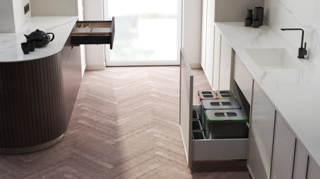 szuflady przystosowane do segregacji śmieci, drewniane wkłady do szuflady na sztućce, wyspa kuchenna, białe meble kuchenne, czarna bateria zlewozmywakowa