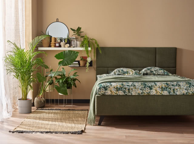 Кровать VOX с мягкой обивкой, зеленая обивка, разноцветное постельное белье, зеленый плед, цветы, полки для безделушек и книг, ковер, зеркало