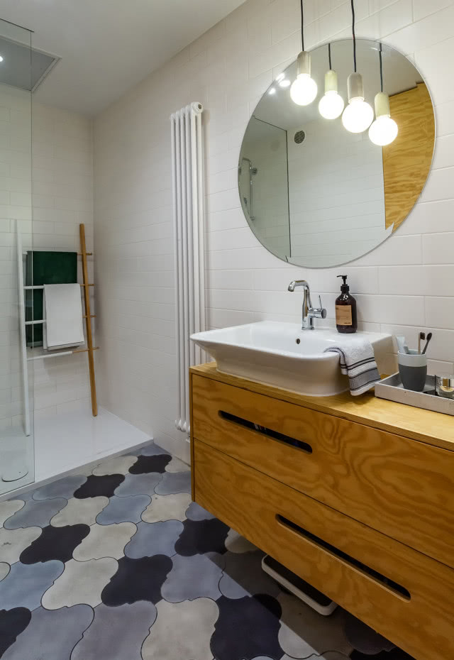 Łazienka z okrągłym lustrem i mozaiką na podłodze