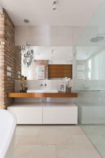 Wystrój łazienki to połączenie surowych materiałów szkła, cegły i ciepłego drewna.