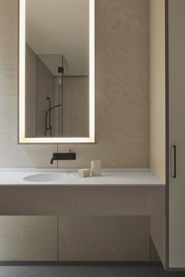 Łazienka z płytkami imitującymi sklejkę i podświetlanym lustrem.