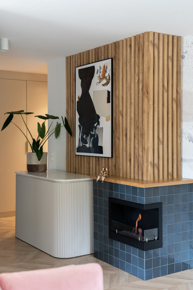 Narożny biokominek wykończony kwadratowymi płytkami w kolorze ciemnego granatu