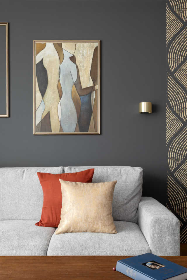 Ciemnoszara ściana w salonie na tle jasnej kanapy