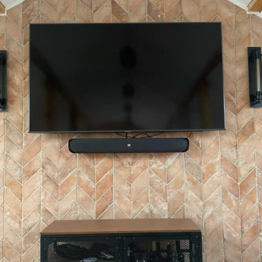 płytka skośna na ścianie, telewizor, kinkiety, regał