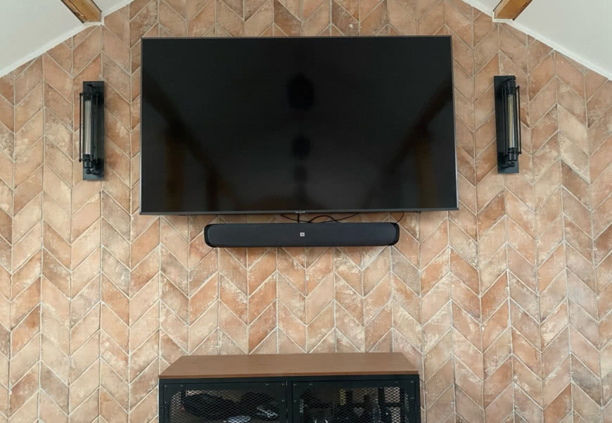 płytka skośna na ścianie, telewizor, kinkiety, regał