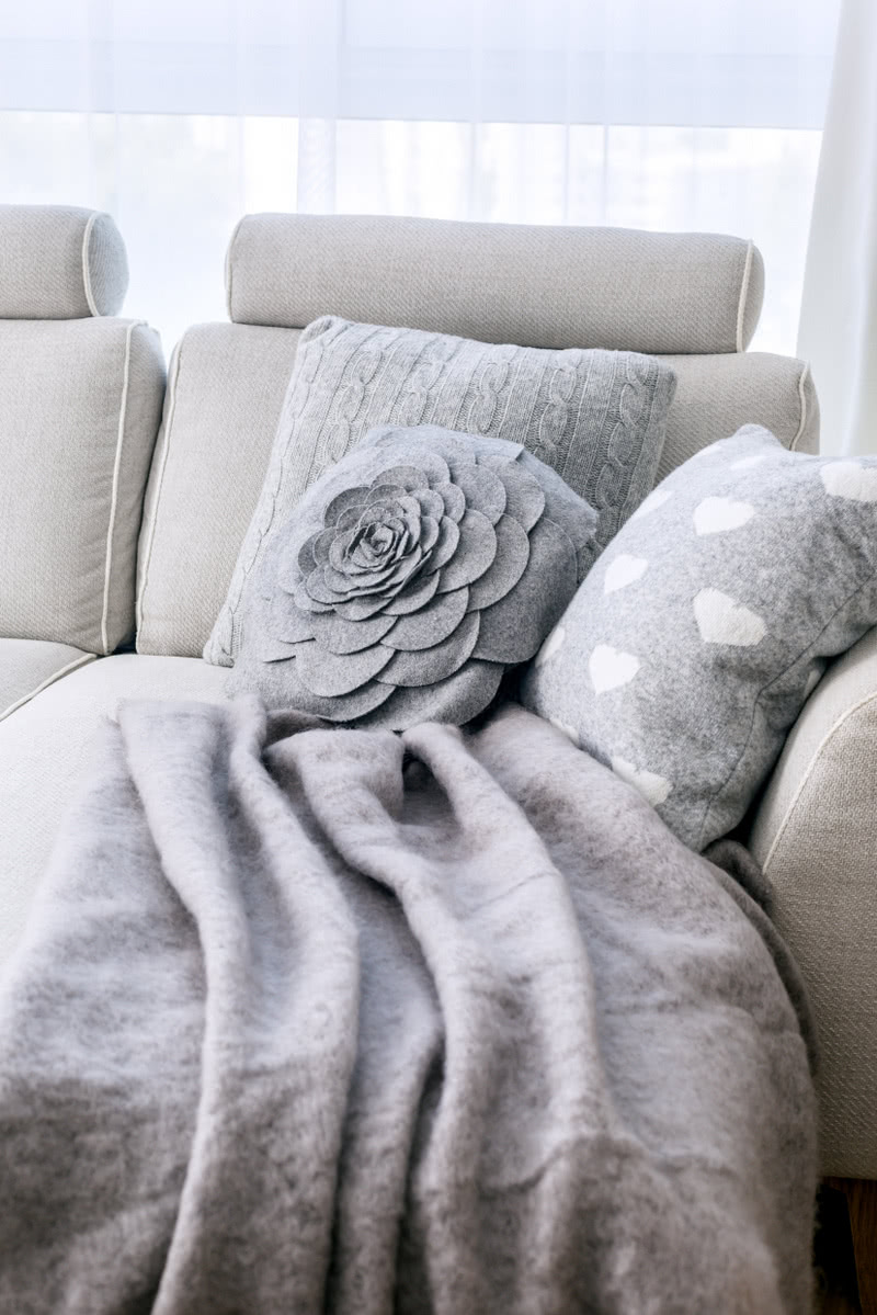 Na jasnoszarej sofie (Inne Meble) szary pled i...