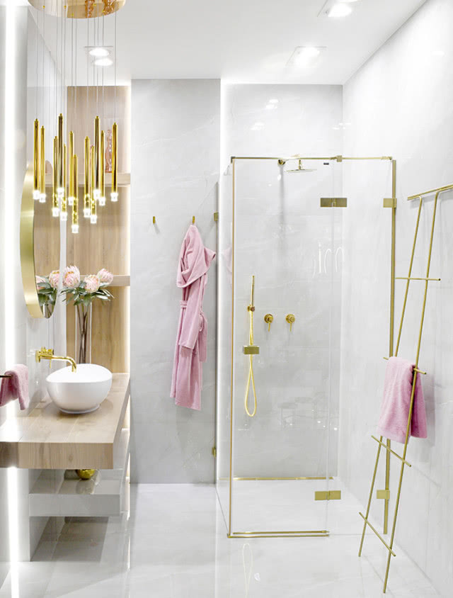 kabina prysznicowa, umywalka nablatowa, złota bateria podtynkowa, drabinka na ręczniki, okrągłe lustro, szlafrok, oświetlenie sufitowe
