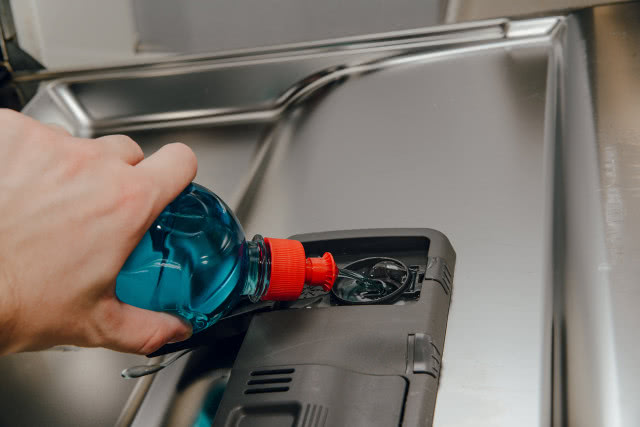 mężczyzna wlewa do zmywarki nabłyszczacz