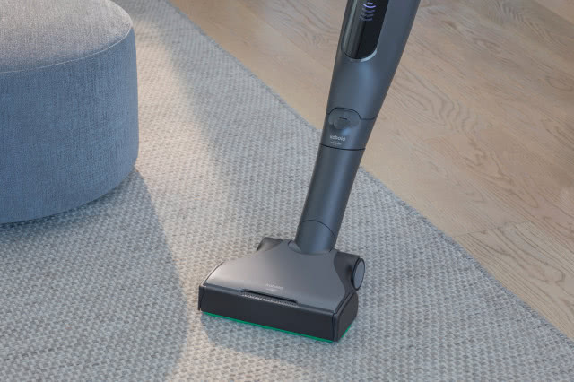 Odkurzacz Vorwerk Kobold VK7 Titanium podczas odkurzania jasnego dywanu w nowoczesnym salonie.