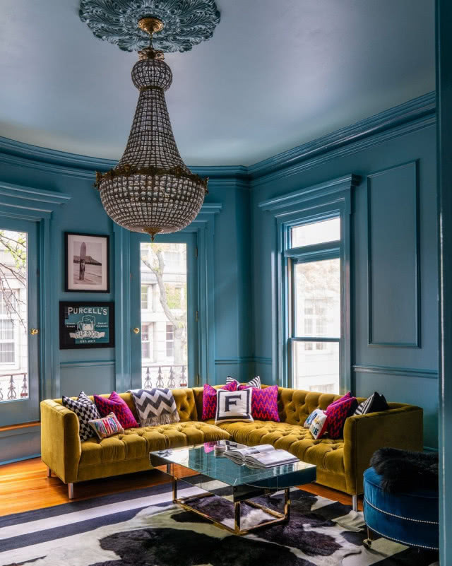 kanapa żółta na tle kobaltowych ścian ze sztukaterią