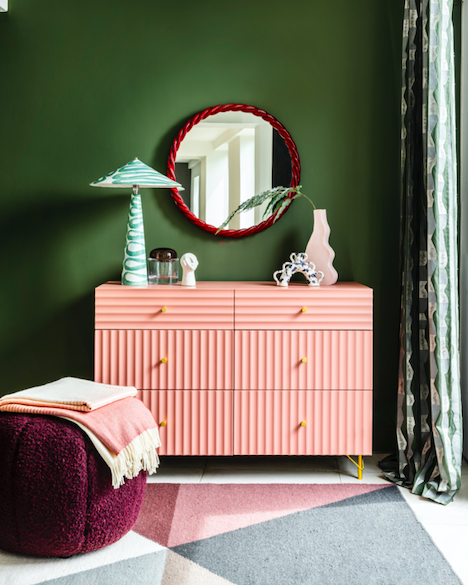 różowa komodą na tle butelkowej ściany