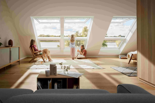 duże okna dachowe, dzieci wyglądające przez okno, Kobieta siedzi na fotelu, dywan, dużo słońca, kanapa, stolik kawowy, komoda