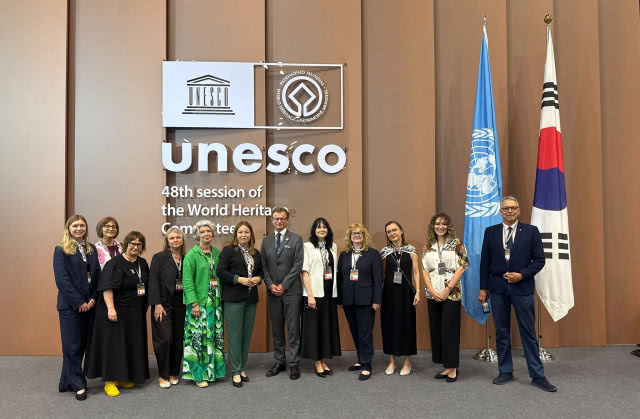 kilka osób pozuje do zdjęcia, stoją pod logo UNESCO