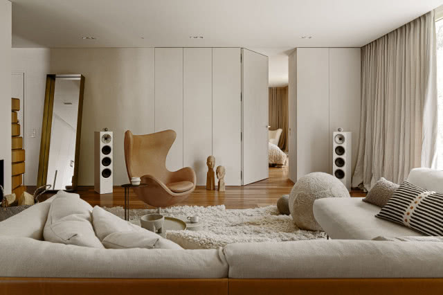 beżowy salon z jasną kanapą i skórzanym fotelem EGG