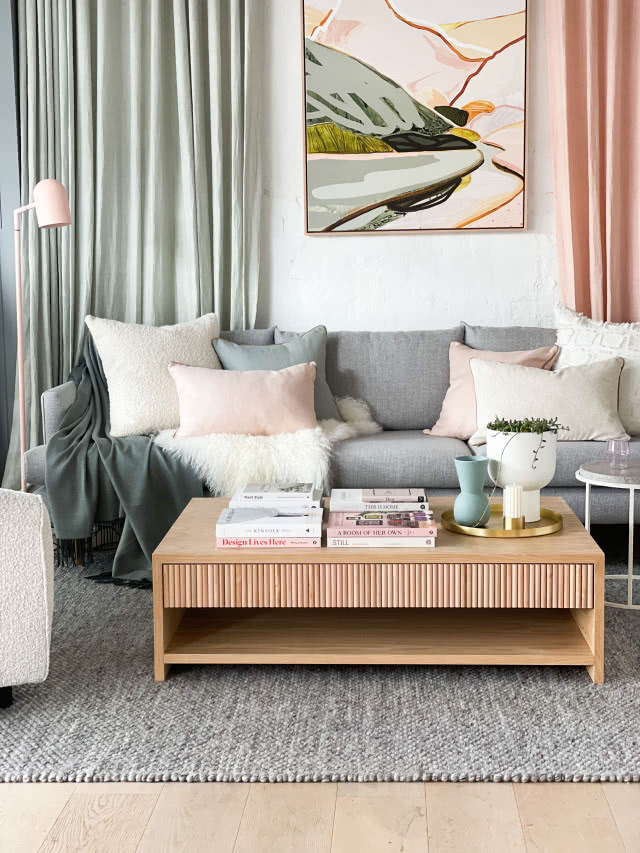 Aranżacja salonu w stylu skandynawskim z szarą sofą i drewnianym stolikiem