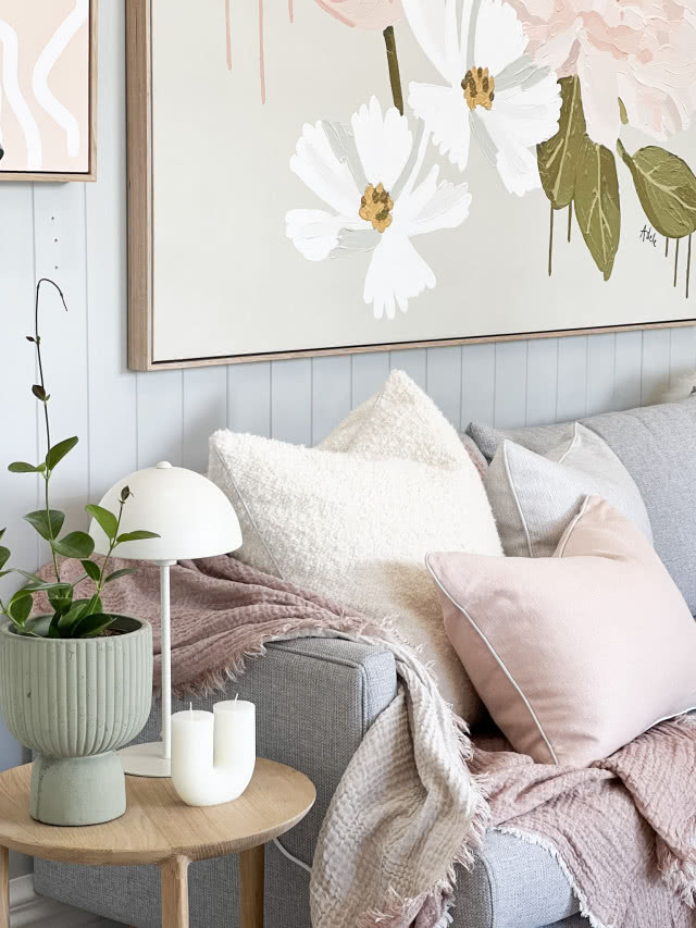 Aranżacja salonu w stylu skandynawskim z szarą sofą i poduszkami