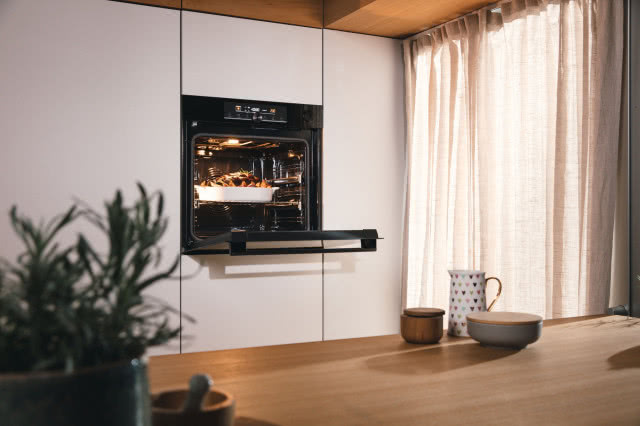 białe frontu kuchenne, piekarnik, drewniany blat, dzbanek, miseczki, zioła, moździerz 